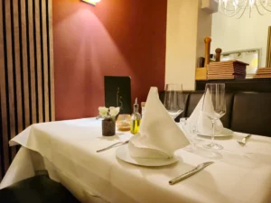 Gedeckter Tisch in einer ruhigen Ecke des Restaurants mit warmer Beleuchtung, roter Wand und moderner Holzdekoration.