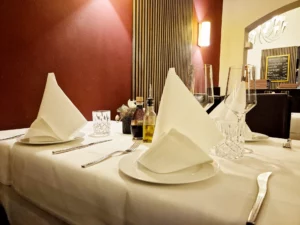 Stilvoll gedeckter Tisch mit weißen Stoffservietten, Weingläsern sowie Olivenöl und Balsamico, bereit für die Gäste.